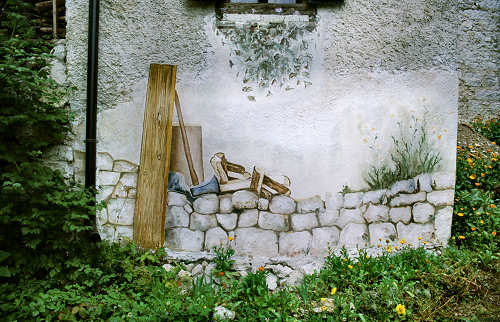 Illusione ottica, un muro dipinto sul muro e rappresentazione dello spaccare la legna
       per la stufa, lavoro quotidiano in tutte le case